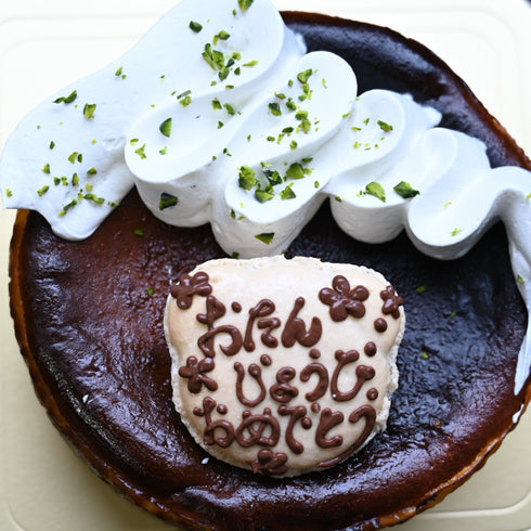 こんがり焼けたピスタチオのバスクチーズケーキ。生クリームと刻みピスタチオ、メッセージマカロンをトッピングして仕上げました。真上からの写真。