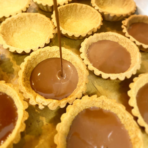 焼き上げたタルト生地に生チョコを流し入れている作業風景。