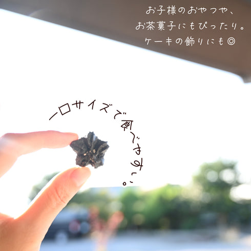 黒胡麻竹炭の心輪くっきい(マカロンラスク)を一粒手に持っている写真。