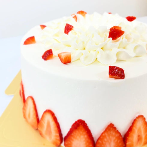 ホールケーキ。米粉のシフォンケーキ生地を真っ白な純生クリームでデコレーション。側面とトップに苺を飾って仕上げたシフォンケーキの写真。