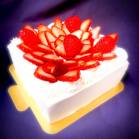 四角いホールケーキ。純生クリームの白いホールケーキの上に苺が飾ってある。四角い形のケーキ。
